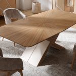 Une table rectangulaire en bois de chêne. Un pied centrale graphique. Le bois du plateau de la table forme un point au centre ou converge les veinages du bois.